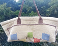 Beige handbag with colorful patterned patches against a natural background