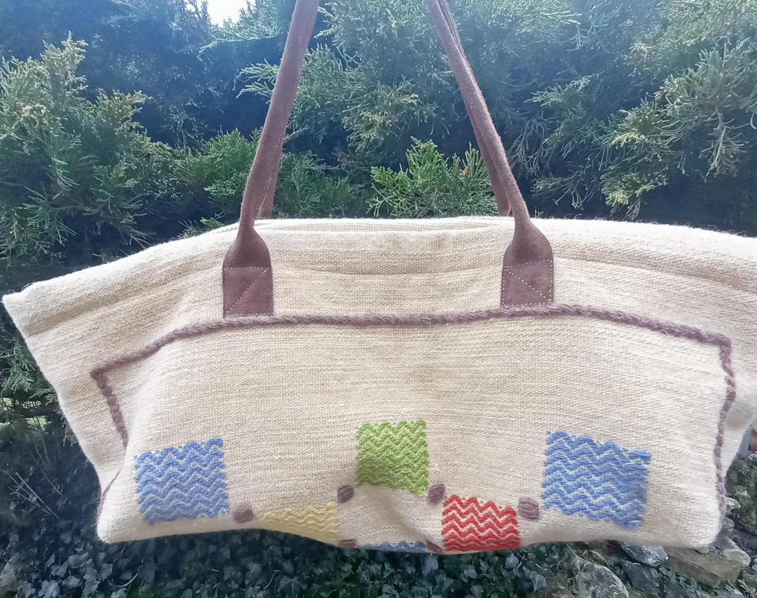 Beige handbag with colorful patterned patches against a natural background